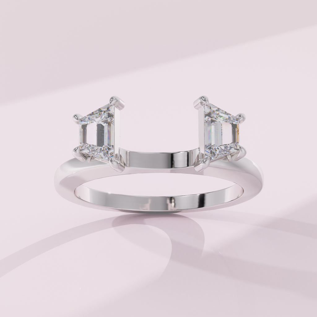 Silver ring with emerald-cut diamonds on a light pink background