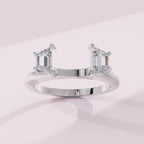 Silver ring with emerald-cut diamonds on a light pink background
