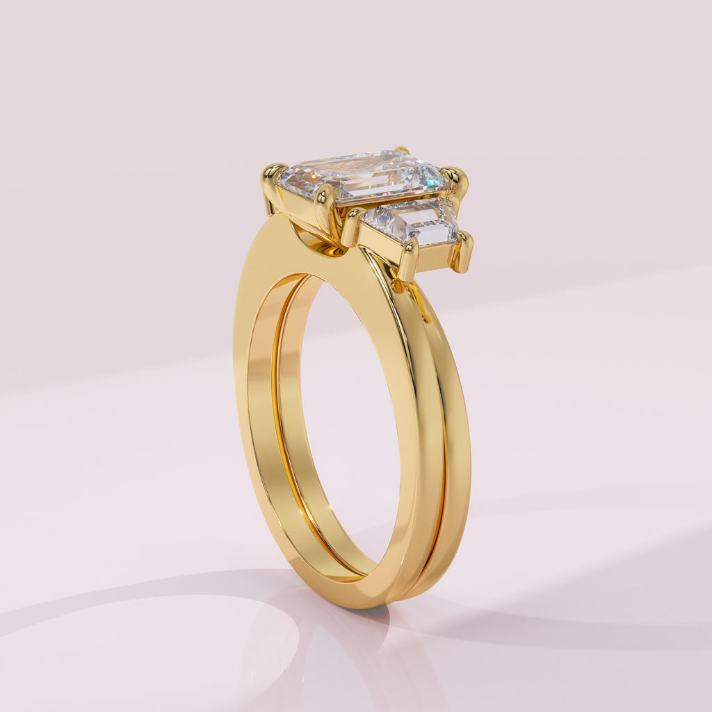 Gold ring with emerald-cut diamond on a light pink background