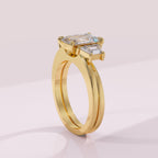Gold ring with emerald-cut diamond on a light pink background