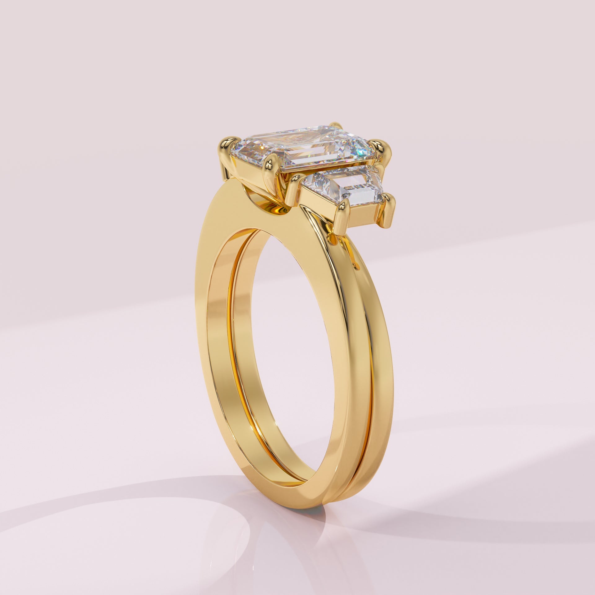 Gold ring with emerald-cut diamond on a light pink background