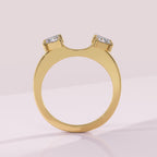 Gold ring with two diamond stones on a light pink background