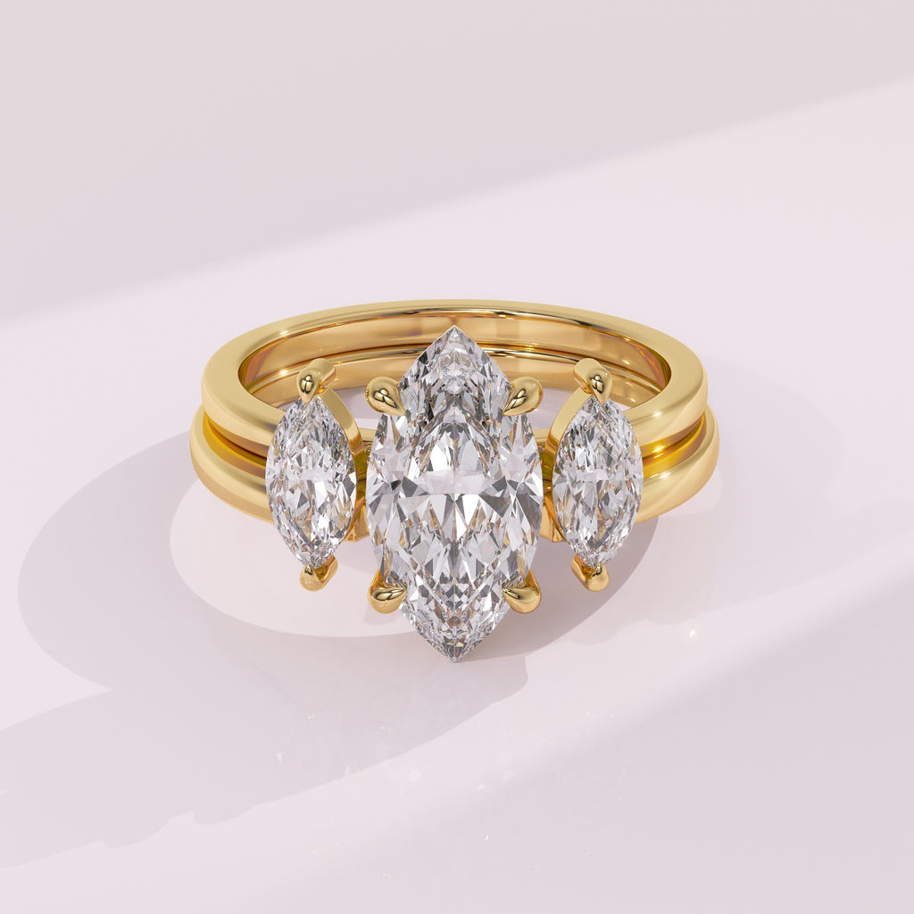 Gold ring with three pear-shaped diamonds on a light pink background