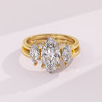 Gold ring with three pear-shaped diamonds on a light pink background