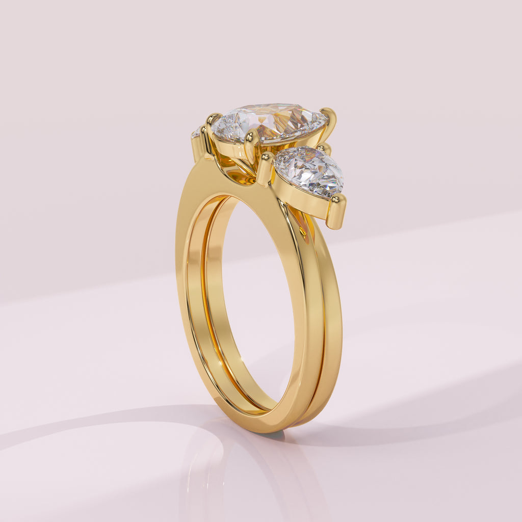 Gold ring with three clear gemstones on a light pink background