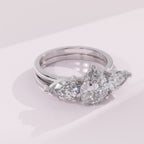 Silver ring with pear-shaped diamonds on a light pink background